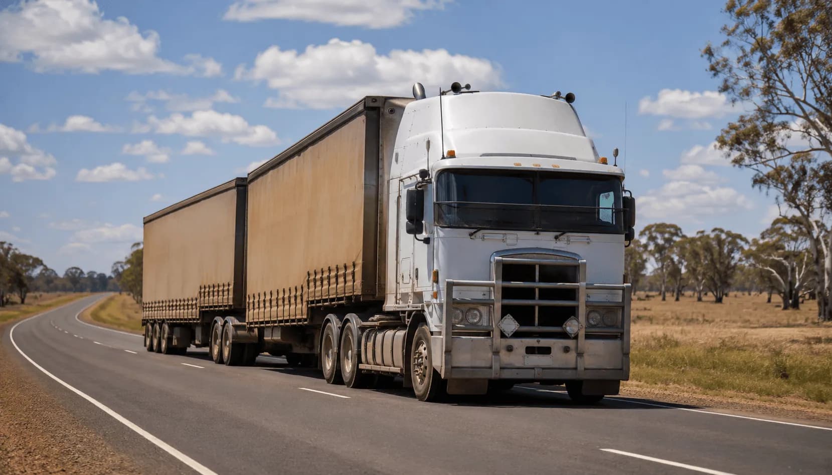 Australian cab-over prime mover hauling a B-double curtainsider on a regional highway
